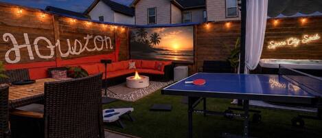 Une terrasse extérieure équipée d’une table de ping-pong, d’un canapé et d’un foyer.