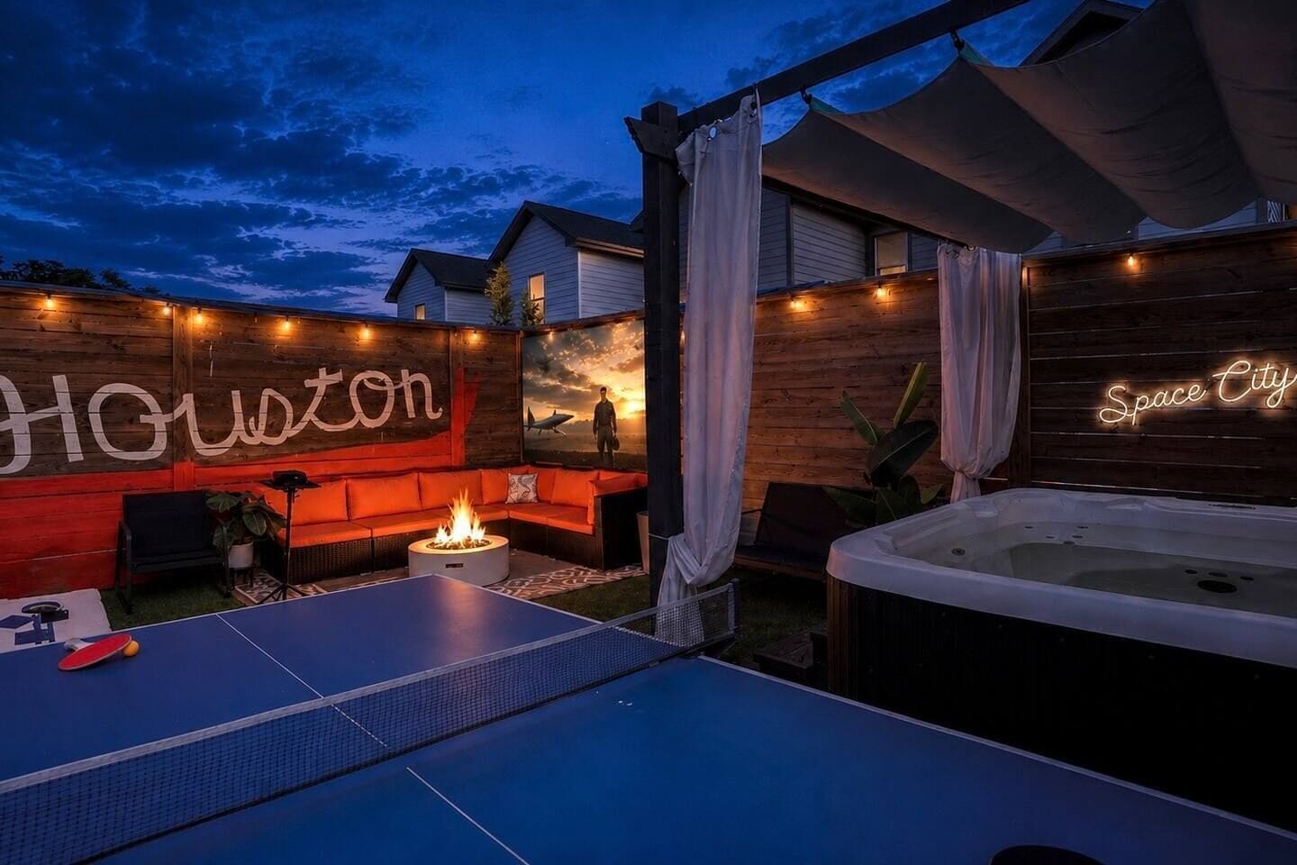 An outdoor patio with a ping pong table, a hot tub, and a seating area with a fire feature.