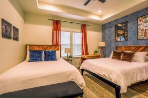 A hotel room with two beds, a bench, a desk, and a patterned wall. - Space City House | Hot Tub + Cinema | Sleep 16+ (Houston)
