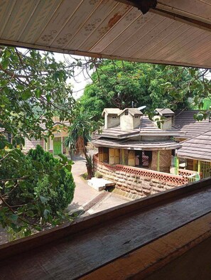 A traditional building with a tiled roof, a courtyard, and a view of greenery.