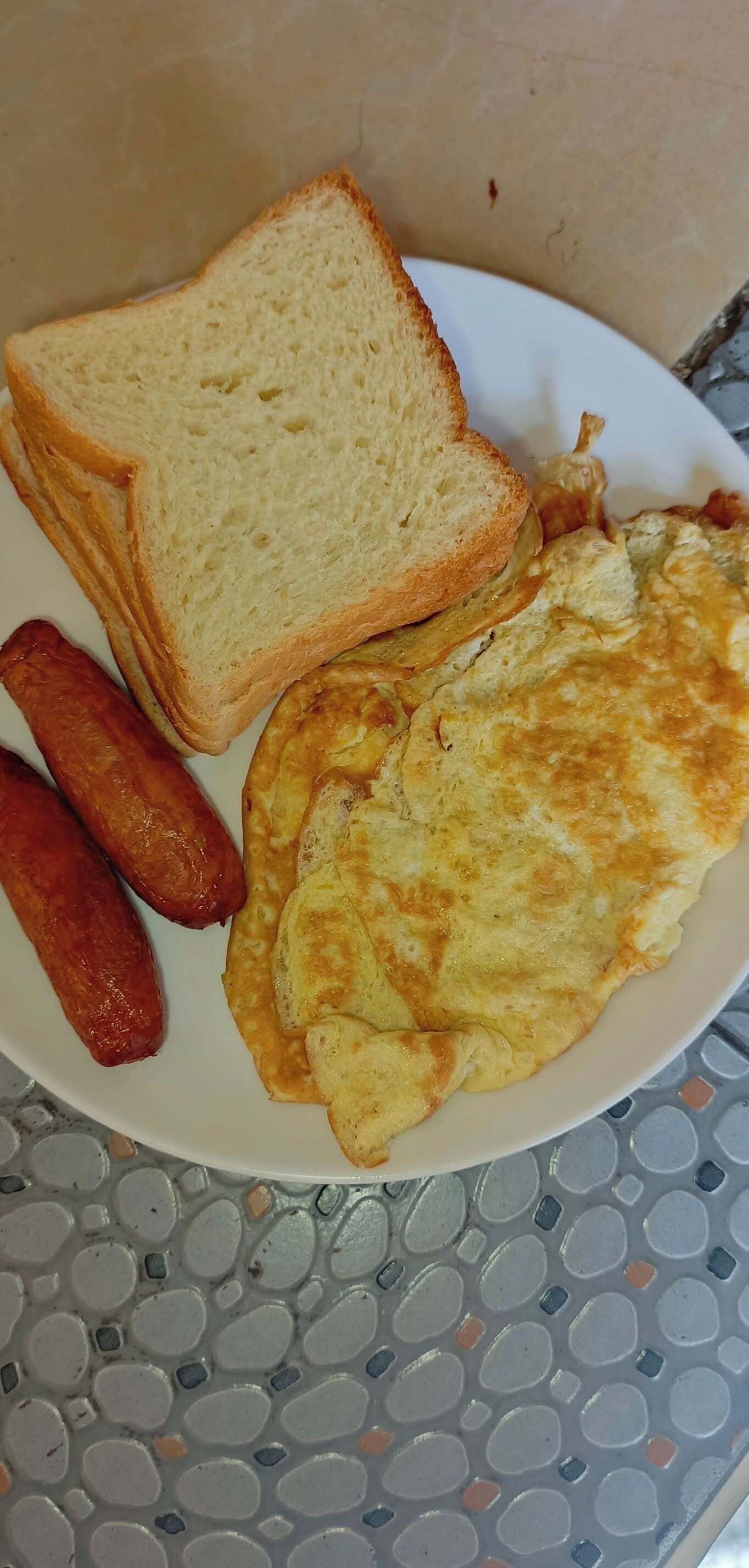 Un plato con tostadas, salchichas y una tortilla.