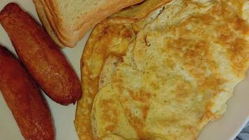 Un plato con tostadas, salchichas y una tortilla.