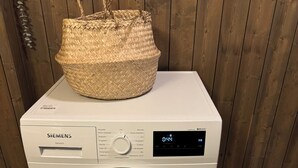 Un lave-linge Siemens, doté d’un panier sur le dessus, est placé contre un mur en bois.