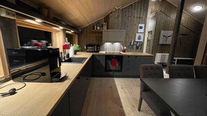 A modern kitchen with wooden cabinetry, a built-in microwave, and a dining area with a table and chairs.