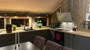 Eine moderne Küche mit Holzwänden, einem Essbereich mit Tisch und Stühlen sowie einem eingebauten Backofen.