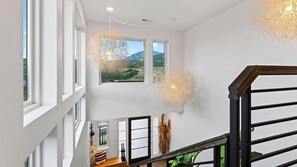 Ein modernes Interieur mit Treppe, großen Fenstern und dekorativer Beleuchtung.