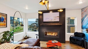 Ein modernes Wohnzimmer mit Kamin, großen Fenstern und Kunstwerken.