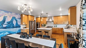 A modern kitchen with wooden cabinets, stainless steel appliances, and a dining area with a table and chairs.