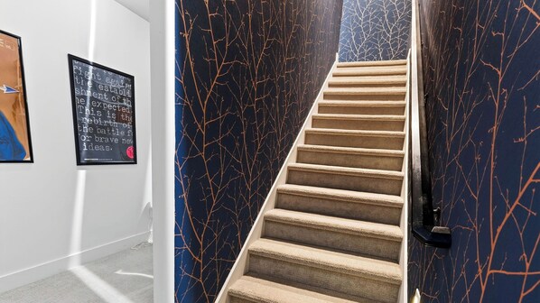 Un escalier avec un mur foncé et une moquette de couleur claire.