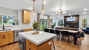 A modern kitchen with a central island, wooden cabinets, and pendant lighting. - Reel & Ridge by Avantstay 2 Hot Tubs + Private Sauna + Movie Room + Fire Pit (Heber City)