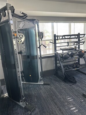 A gym with a squat rack, bench press, and weightlifting equipment. - Cozy 1-bedroom apartment 4 mins from galleria mall Houston location (Houston)