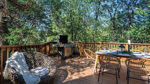 Eine Terrasse im Freien mit Grill, Korbmöbeln und einem Essplatz für zwei Personen.
