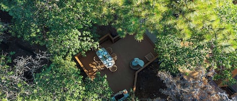 An aerial view of a deck with a table and chairs, surrounded by dense foliage.