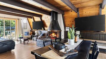 Una sala de estar acogedora con chimenea, vigas de madera, un sofá y un comedor.