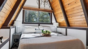 Ein Schlafzimmer mit einem Bett, Nachttischen, einem Fenster und einer Kristallleuchtre.