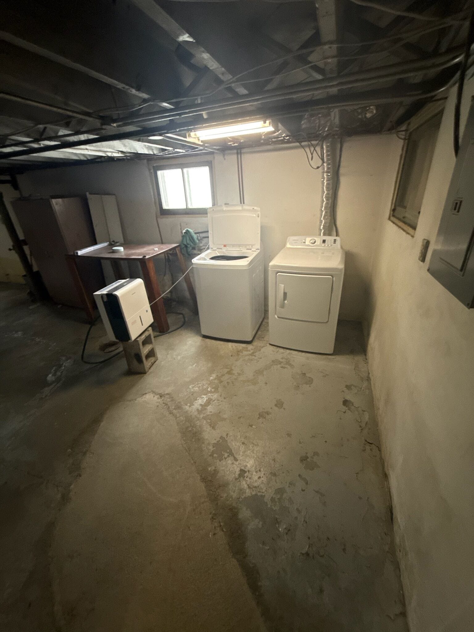 A basement utility room with a washing machine, a dryer, and a water heater.