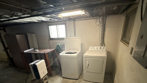 A basement utility room with a washing machine, a dryer, and a water heater.