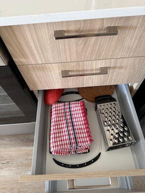A drawer with a red and white checkered cloth and a metal grater. - Chic Urban 2BR Apt with Balcony and Skyline Views (Ottawa)