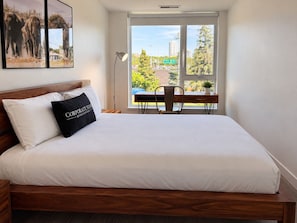 A bedroom with a bed, a desk, and a chair. - Chic Urban 2BR Apt with Balcony and Skyline Views (Ottawa)