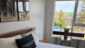 Une chambre d’hôtel avec un grand lit, une fenêtre donnant sur le paysage urbain et un fauteuil près de la fenêtre.