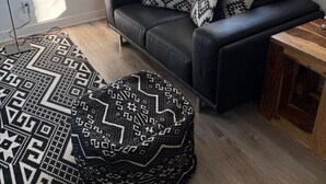 Un salon moderne avec un canapé, un tapis à motifs et une grande fenêtre.