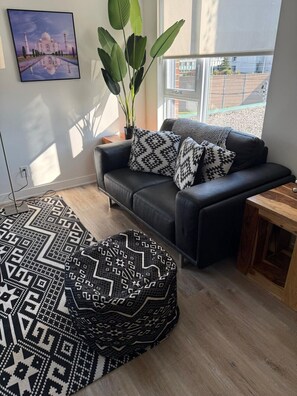 Ein modernes Wohnzimmer mit einer Couch, einem gemusterten Teppich und einem großen Fenster.
