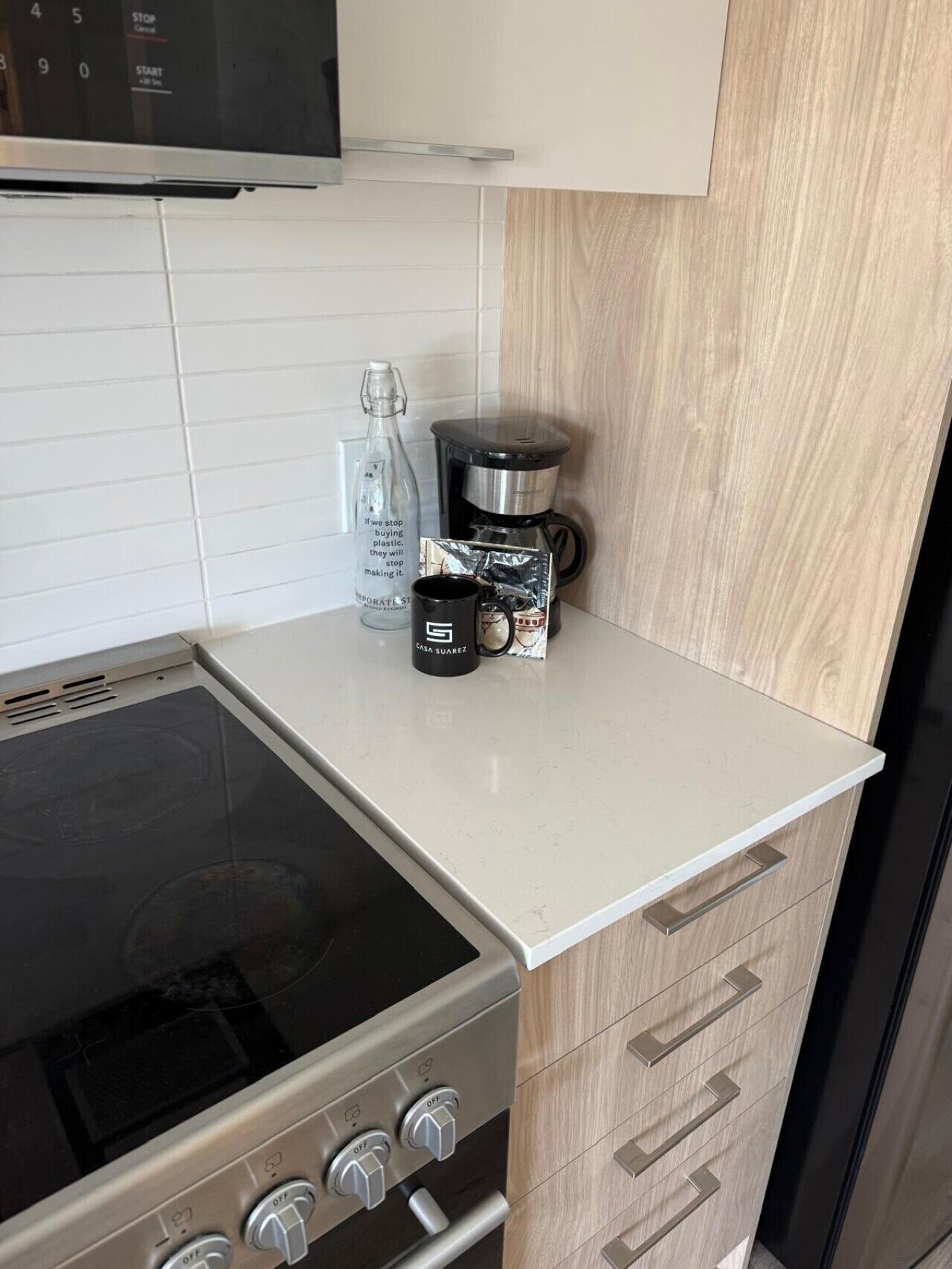 A kitchen with a stove, microwave, and a coffee maker on the counter.
