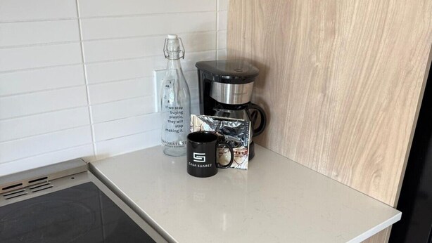 Une cuisine équipée d’une cuisinière, d’un four à micro-ondes et d’une machine à café posée sur le plan de travail.