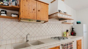 Una cocina con dos fregaderos, armarios de madera, una estufa a gas y un refrigerador.