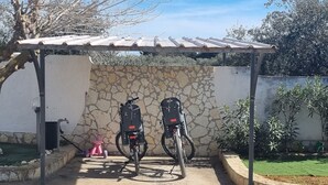 Dos bicicletas estacionadas bajo una estructura cubierta con un muro de piedra y un tejado de baldosas.