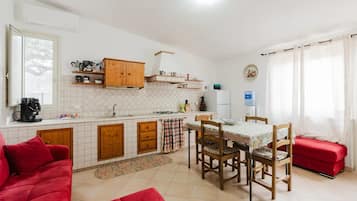Cozinha compacta com armários de madeira, uma mesa de jantar e um sofá vermelho.