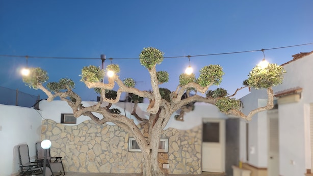 A tree with multiple lights in a courtyard with stone walls and outdoor furniture. - Charming Villa Rental in Mazara Del Vallo With Pool Access (Mazara del Vallo)
