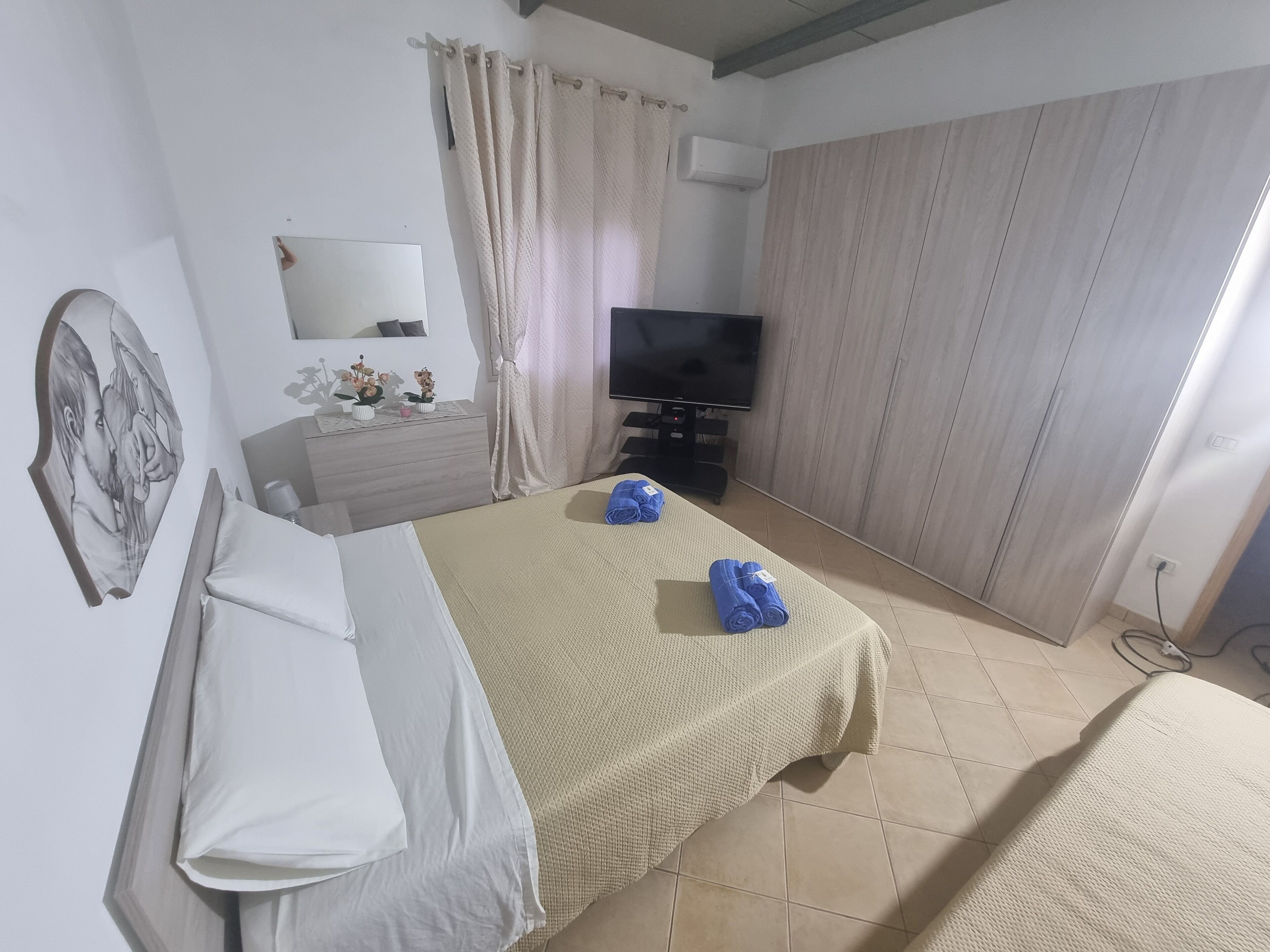Ein Hotelzimmer mit Bett, Fernseher, Kommode und Spiegel.
