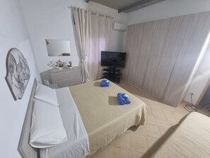 A hotel room with a bed, a television, a dresser, and a mirror. - Charming Villa Rental in Mazara Del Vallo With Pool Access (Mazara del Vallo)