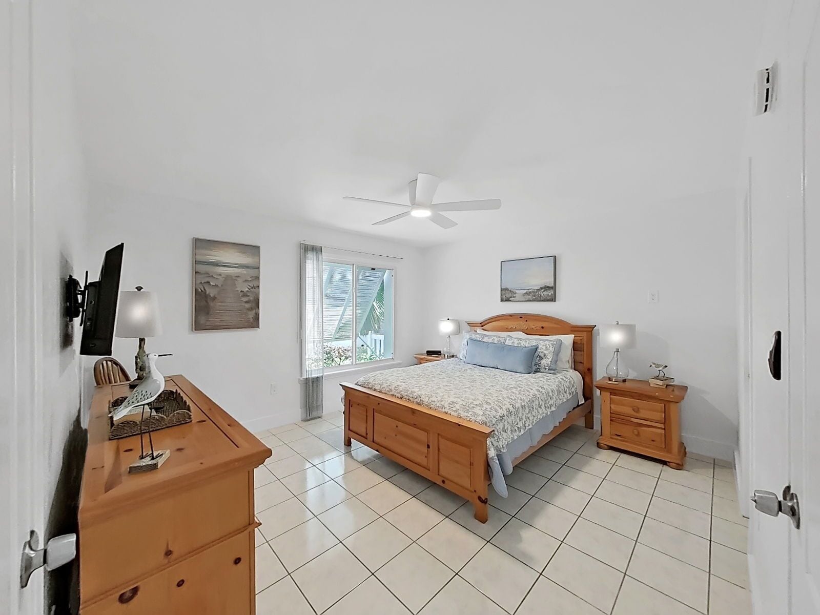 A bedroom with a bed, bedside tables, a desk, a chair, a window, and a ceiling fan.