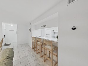 Eine moderne Küche mit weißer Arbeitsplatte, Holzbarhocker und einem eingebauten Backofen.