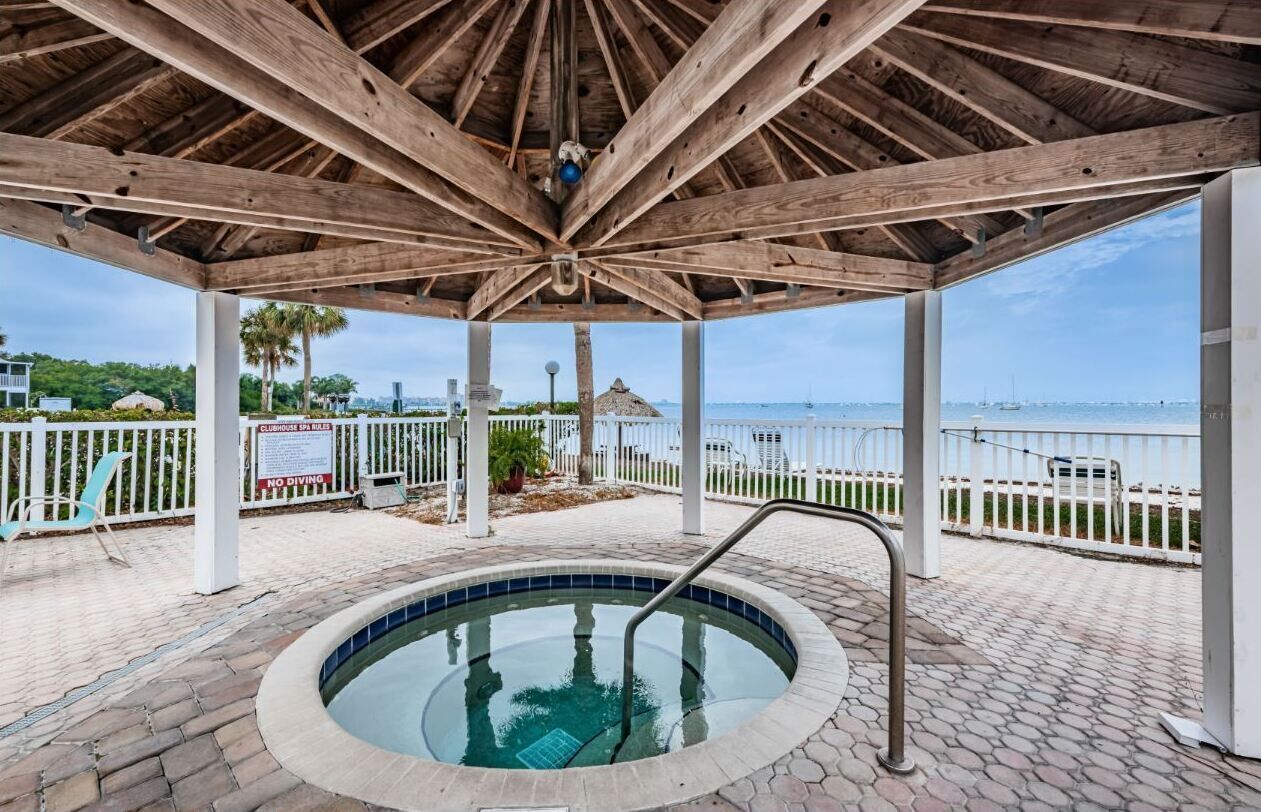 A covered outdoor swimming pool with a wooden roof, a view of the sea, and a sign indicating no diving.