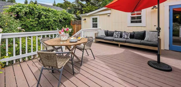 A wooden deck with a table and chairs, a sofa with cushions, and a red umbrella. - Heart of Sonoma Wine Country, Kenwood (Kenwood)