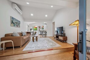 A spacious living room with a sofa, coffee table, and TV. There is a kitchen in the background with a dining area. - Heart of Sonoma Wine Country, Kenwood (Kenwood)