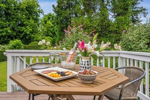 A wooden deck with a table set for a meal, featuring a plate of food, a bowl of fruit, and a vase with flowers. - Heart of Sonoma Wine Country, Kenwood (Kenwood)