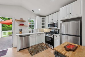 A modern kitchen with white cabinets, stainless steel appliances, and a wooden dining table. - Heart of Sonoma Wine Country, Kenwood (Kenwood)