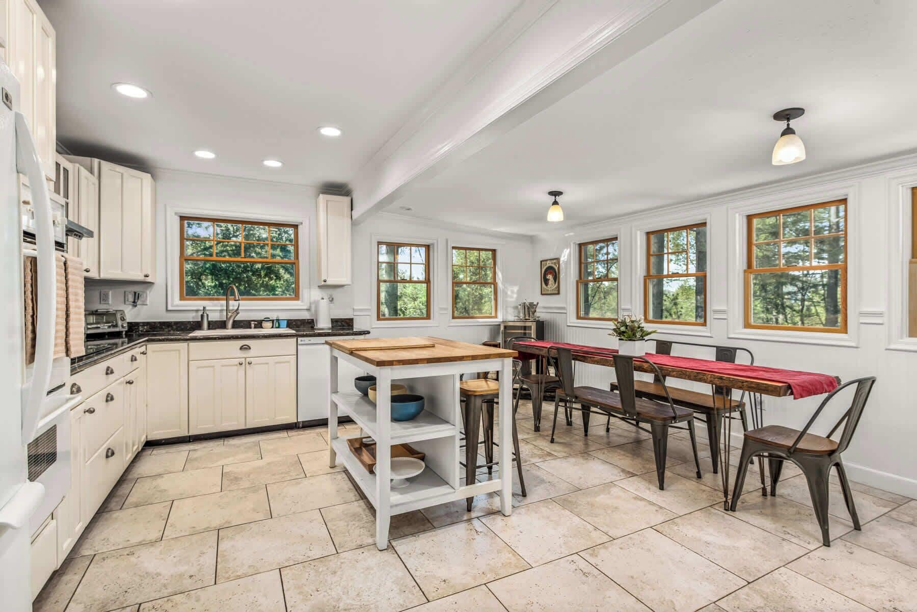 A kitchen with white cabinets, a wooden island, and a dining area with a red tablecloth.
