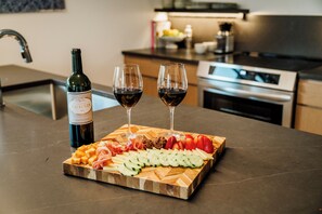 A wooden board with cheese, cured meats, and sliced fruits on a kitchen counter. - NEW Cozy Carriage House in Congress Park - Denver (Denver)