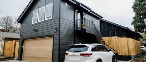 A modern two-story house with a garage, a balcony, and a staircase leading to the upper floor.