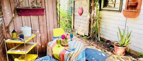 Uma área de estar acolhedora ao ar livre, com mesa, cadeiras e um pequeno jardim.