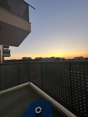 Een terras op het dak met een blauwe tafel en een metalen hekwerk.
