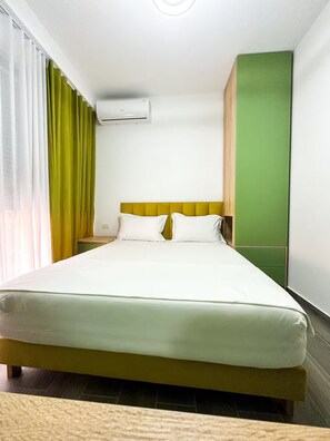 A hotel room with a bed, a nightstand, a green wall, and an air conditioning unit. - Hodo Apartments | Modern Cozy Apartment in Tirana 15 mins away from city Centre! (Tiranë)