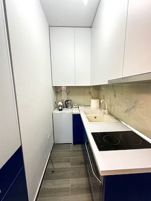 A compact kitchen with white cabinets, a built-in stove, and a sink. - Hodo Apartments | Modern Cozy Apartment in Tirana 15 mins away from city Centre! (Tiranë)