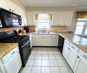 A kitchen with white cabinetry, a black stove, a sink, and a window with a patterned valance. - Stunning view of the North Golf Course from the back deck. (Cherokee Village)