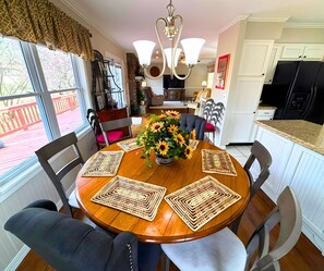 A dining area with a round wooden table, six chairs, and a vase of sunflowers. - Stunning view of the North Golf Course from the back deck. (Cherokee Village)